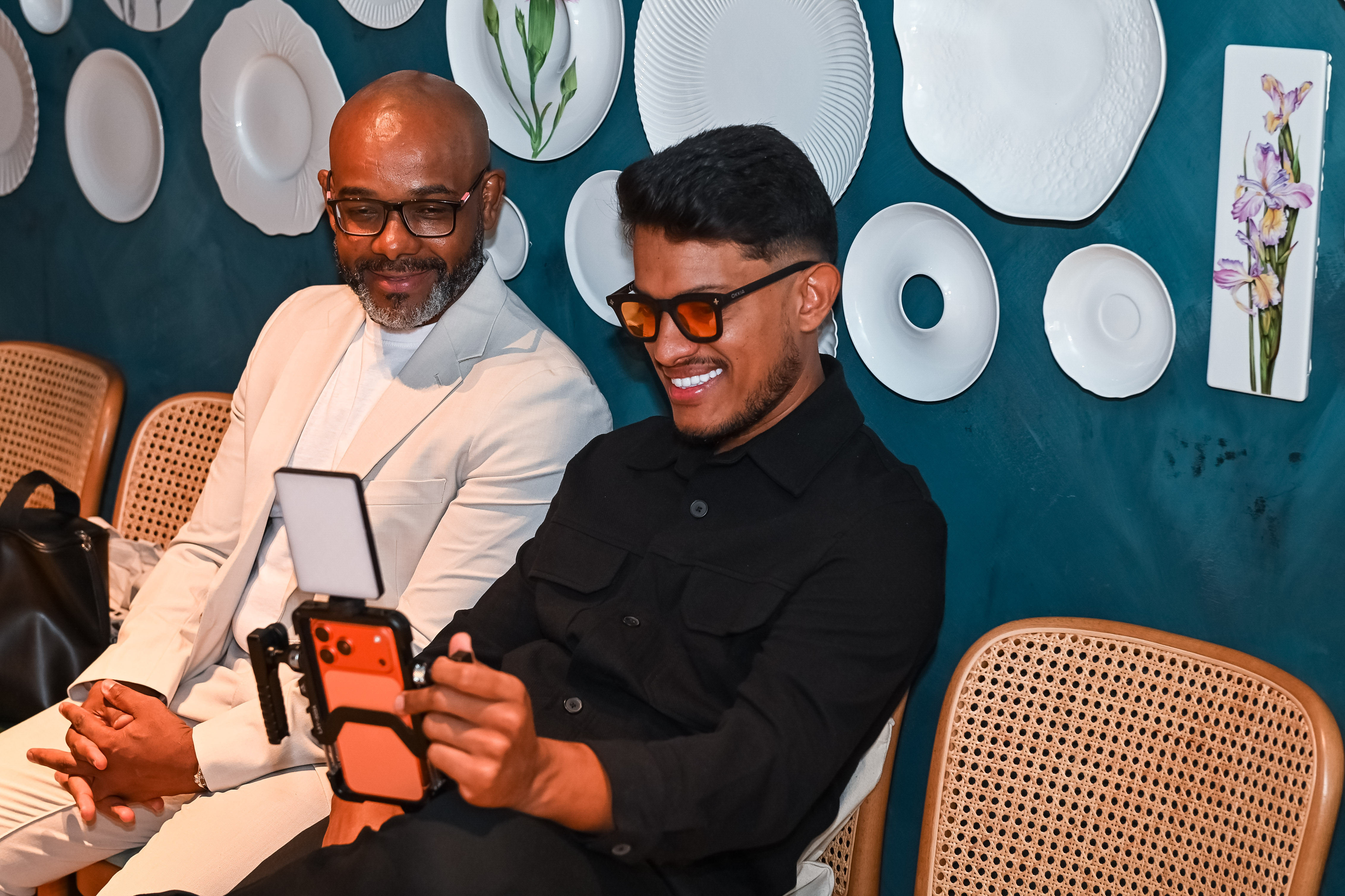 Vinicius Xavier com celular em suporte e painel de iluminação durante uma produção de vídeo.